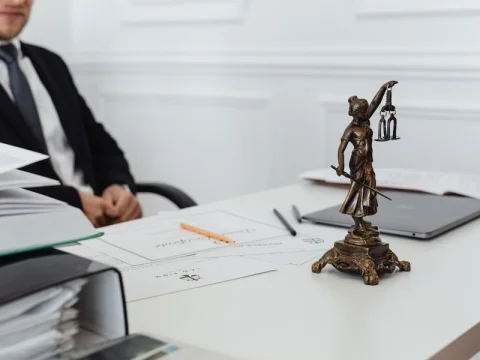 Lady Justice statue on a desk beside legal documents